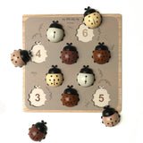 Découvrez Mes Dames 🐞, un puzzle Montessori en bois pour développer motricité, reconnaissance des formes et premiers chiffres dès 3 ans.