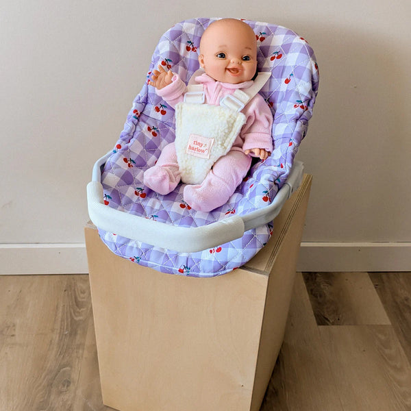 Coquille Tiny Harlow Vichy lilas et cerise pour transporter votre poupée partout. Poignée, sangles sécurisées et housse amovible lavable. Jouet d’imitation pour enfants dès 3 ans.
