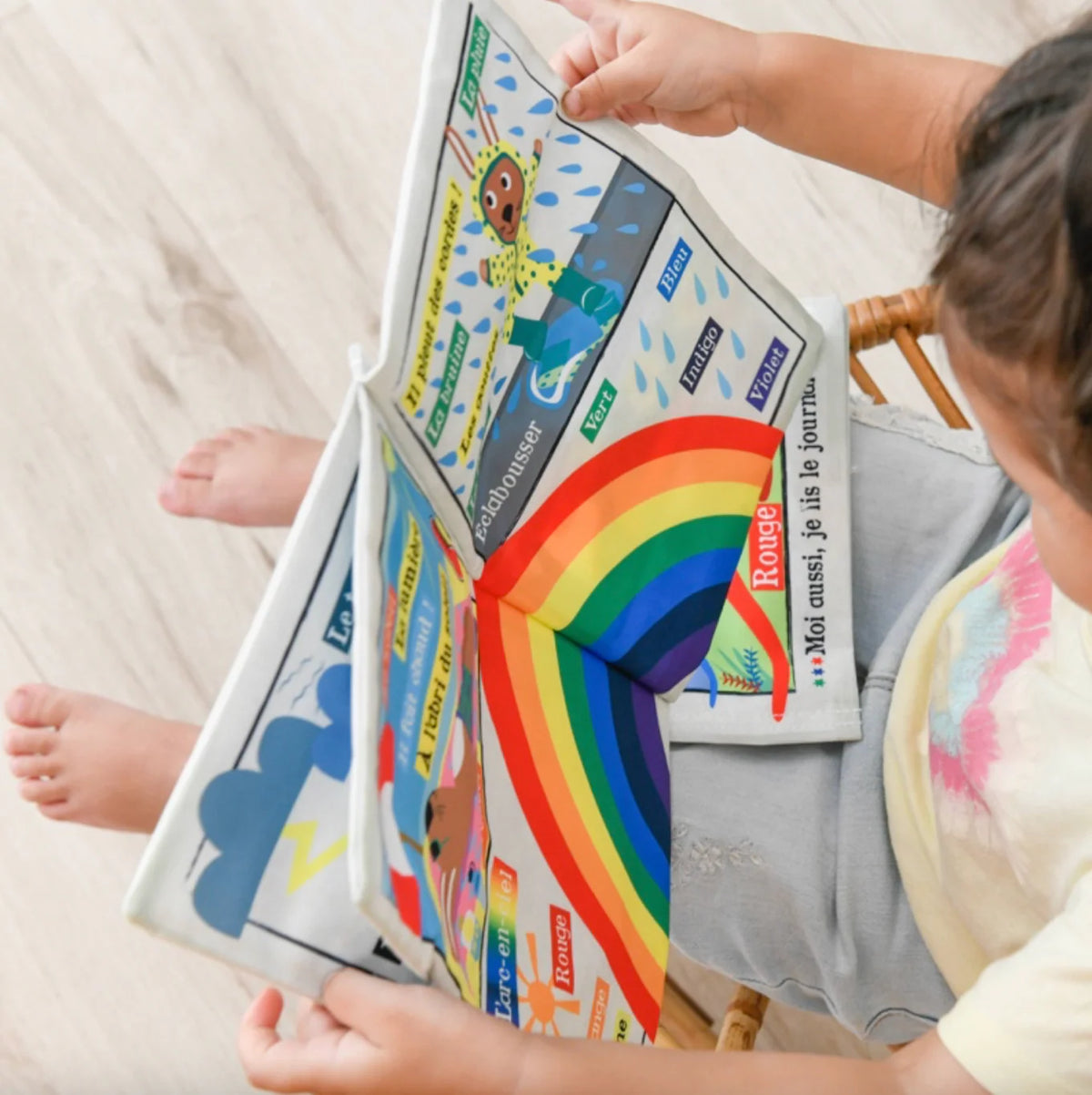 Bébé manipulant journal en tissu météo, exploration tactile sécurisée